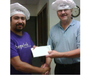 Dale Amundsen (right) presents a check to Hopelink’s Rus Sudakov at the  Evergreen Washelli Bothell funeral home’s annual Chilifest