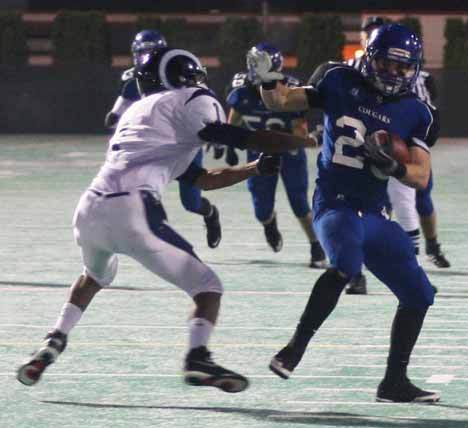 Bothell High senior wide receiver Bobby Gagnon fends off a Rogers High defender on his way to a touchdown during the second quarter of Friday night's 57-14 Cougar victory in the opening round of the 4A state playoffs at Pop Keeney Field. No. 1-ranked Bothell upped its record to 11-0.