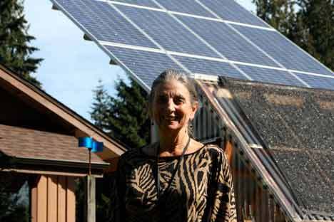 Diane Galante stands in front of Whole Earth Montessori School’s solar panel. The Bothell school’s new building is to the left