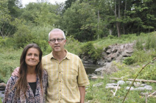 Tom Campbell and wife Stephanie Sarantos stand down hill from their remodeled farmhouse by the stretch of North Creek — in unincorporated Snohomish County — they hope to restore. TOM CORRIGAN
