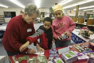 Volunteer Mary Lanphear helps Rebecca and William Nsubuga Christmas shop for their family at Canyon Creek Elementary Dec. 16. Rebecca and William were shopping for their uncle