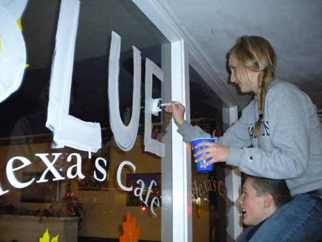 Bothell High students Rachel Fillman and Brad Joyner paint the Cougars' 'Blue Train' slogan on the window front of Alexa's Cafe on Main Street Tuesday night.