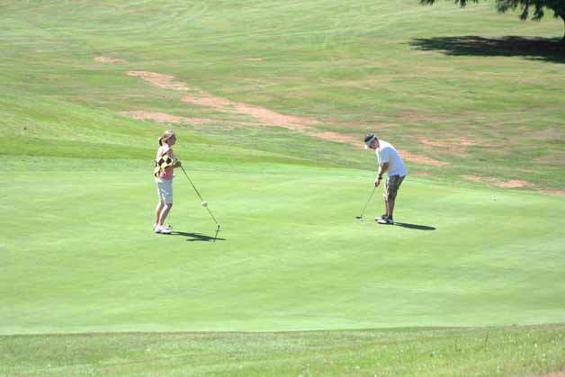 A pair of golfers putt out on the second hole last Friday at Wayne Golf Course in Bothell.