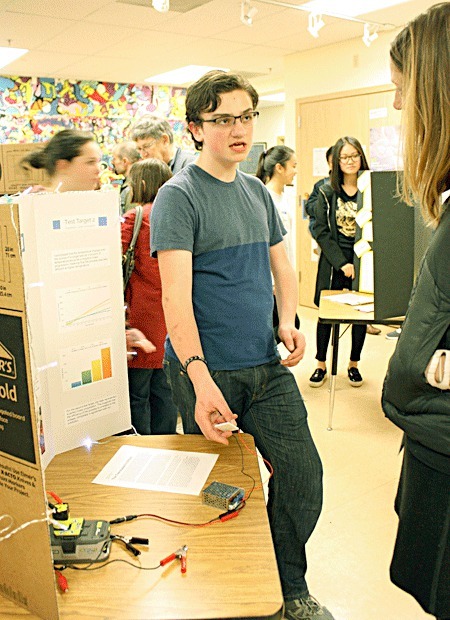 A Woodinville Montessori student explains his science fair project to a teacher.