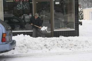 Cuong Tran shovels snow off the sidewalk in front of Lovely Nails Spa in downtown Bothell on Monday morning.