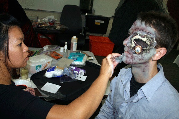 Bastyr University student Jamie Kunkle gets his makeup for Haunted Trails painted on by students Phonexay Simon.