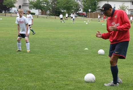 Arsenal Soccer Schools director of coaching Peter Kirov shouts directions as Nathan Willet prepares to get in on the action during this morning's session at Forsgren Park in Bothell. Kirov and coaches from the Hawaii Arsenal branch are putting on the two-week camp through the Northshore Youth Soccer Association. Today