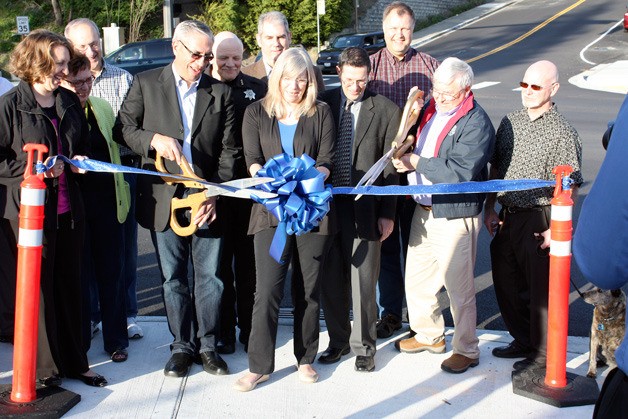 Kenmore City Councilmember Laurie Sperry holds the bow while Councilmembers Glenn Rogers and Allan Van Ness cut the ribbon for the intersection improvements at 61st Ave NE and NE 181st Street.