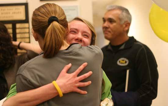 Inglemoor High senior Tansey Lystad hugs cross-country assistant coach Kelly Richards this morning after signing her letter of intent to run at Cal Poly San Luis Obispo next season. Lystad won the 4A state cross-country title in November. To the right is head coach Frank Shuck.
