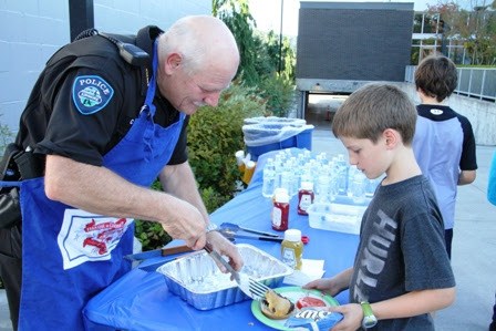 Kenmore Police Chief Cliff Sether serves up a burger to this young citizen during the 2014 National Night Out Against Crime.
