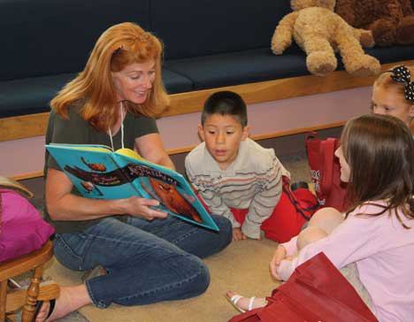 Christopher Villegas Correa is intrigued by the story teacher Paula Wilson is reading at the Woodmoor Elementary Summer Open Library (SOL). Also pictured are Elena Stojakovic and Katie Jeske.