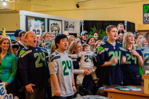 Seattle Seahawks fans sporting Marshawn Lynch jerseys yell “Sea” … “Hawks” last Friday night at the Volume 12 store in Redmond Town Center. A store employee took a picture of the group of about 50 fans to make into a poster and present to Lynch.