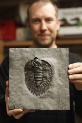 Matt Heaton holds a trilobite fossil at his home in Bothell.