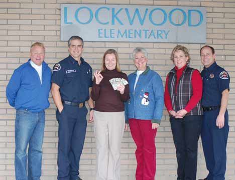 Bothell firefighters gather with Lockwood Elementary employees to hand off some holiday cash.