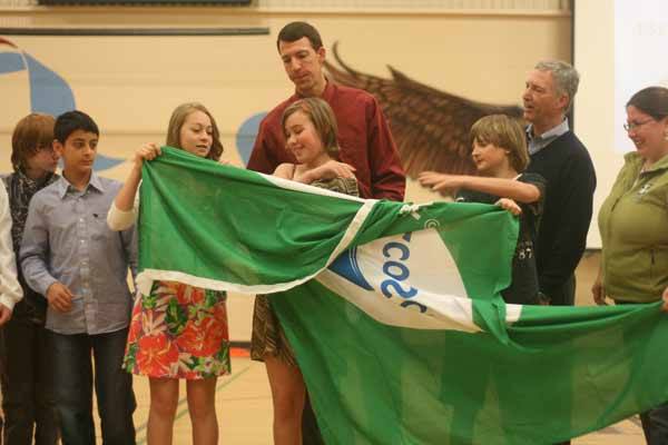 Skyview Junior High Green Team students unfurl the school's Green Flag at this morning's presentation while instructors Tom Nowak