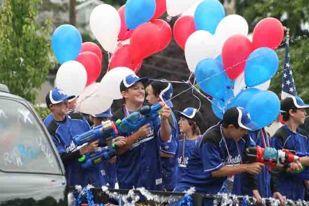 Members of a North Bothell Little League all-stars team spray the crowd with water guns during the City of Bothell 4th of July Grand Parade Sunday on Bothell Way Northeast. The city's Freedom Festival