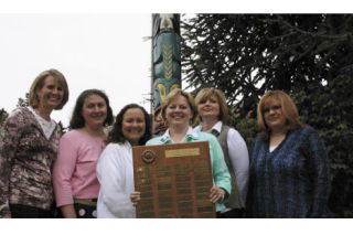Standing in front of the totem pole that decorates the front of Kenmore’s Arrowhead Elementary School are the members of the school’s PTA executive team