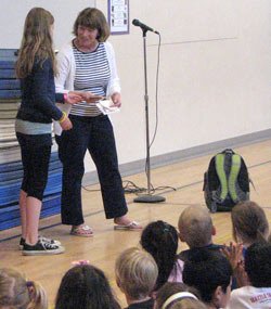 A Lockwood Elementary School student presents one of two checks that went to Hopelink and the Backpacks for Kids program June 21.