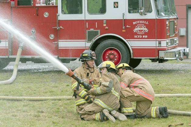 An instructor assists as two WANIC students work a fire hose in the program’s fire and EMS course.