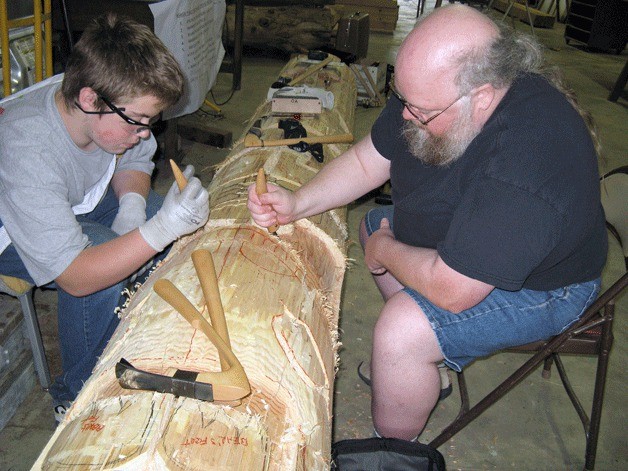 Scout Thomas Lane of Troop 582 and Frank Long work on carving a totem pole.