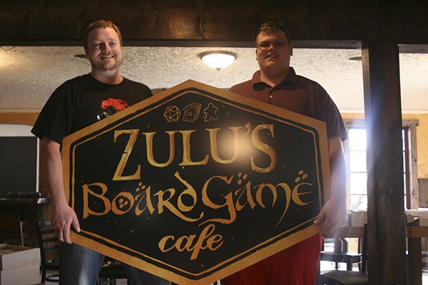 Matt Zaremba (left) and Kaleb Muse showcase the new Zulu's Board Game Cafe sign.