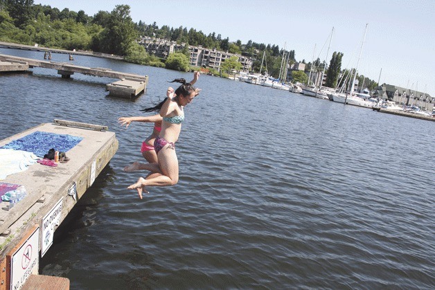 Local teenagers attempt to beat the heat on Tuesday by leaping to Lake Washington from the pier at Log Boom Park. Temperatures reached into the 90s on Monday