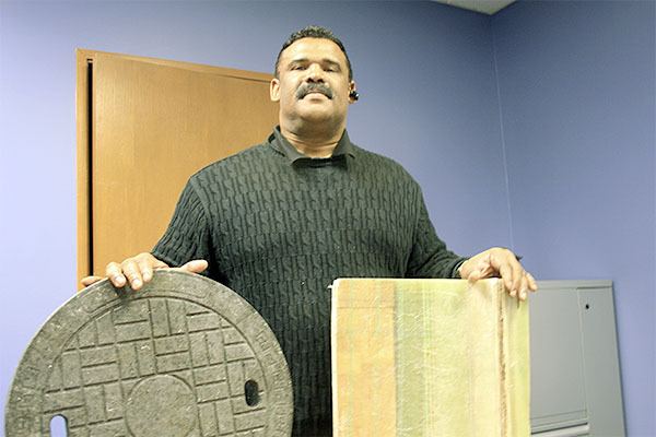 Don Lilly showcases a prototype manhole cover (left) constructed from old wind turbine blades (right).