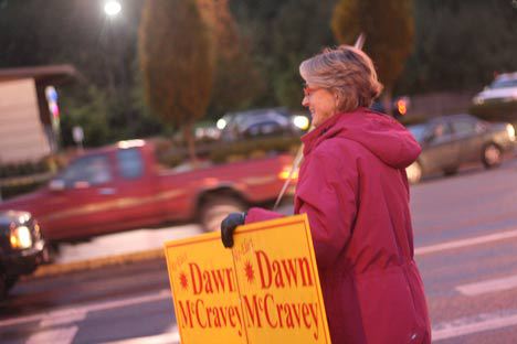 Val Kelly waves a Dawn McCravey sign on 228th Street Southeast in Bothell on Nov. 7.