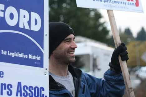 David Vliet of Bothell raises election signs and smiles at drivers while standing on the middle crosswalk waiting area at the intersection of state routes 522 and 527 at 8:30 a.m. this morning.