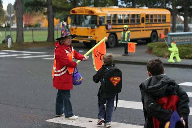 Para-educator Jan Schroeder gets in the Halloween spirit by sporting a colorfully cobwebbed witch hat and handing out candy while helping kids cross the street this morning at Westhill Elementary in Bothell. When she's not on crosswalk duty