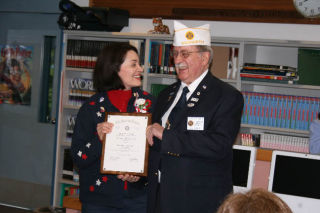 Lockwood teacher Kathy Coyne accepts an Educator of the Year award from American Legion Department of Washington officer Harry Brown III during an April 15 ceremony at her school.