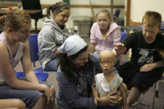 Reagan Ingersoll practices choking remedy on a dummy as Rebecca Samuelson