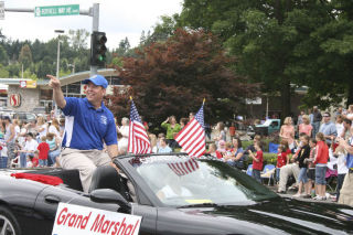Bothell High football coach Tom Bainter points to a friend in the crowd while cruising up Bothell Way Northeast as grand marshal of the Fourth of July Grand Parade last Friday. Festivities also included a Children’s Parade. For more photos