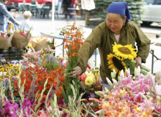 Kaying Chang makes a bouquet to sell at her flower booth Aug. 8 during the Bothell Farmers Market at Country Village.