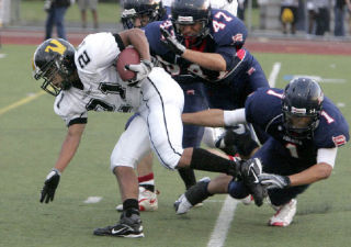 Inglemoor High’s Austin Terry carries the ball as the Juanita High defense knocks him to the ground during first-quarter action Sept. 5 at Juanita. The Vikings won