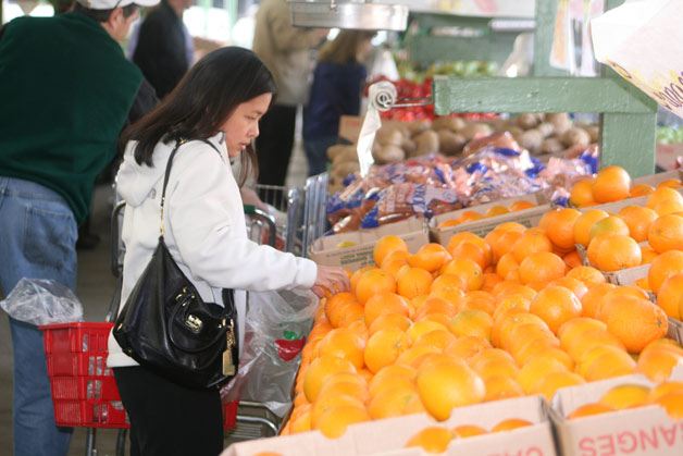 Mae Santos of Bothell combs the orange bin last Wednesday afternoon during the yearly reopening of the Yakima Fruit Market at 17321 Bothell Way N.E. Ken and Marie Lynch built the market in 1950