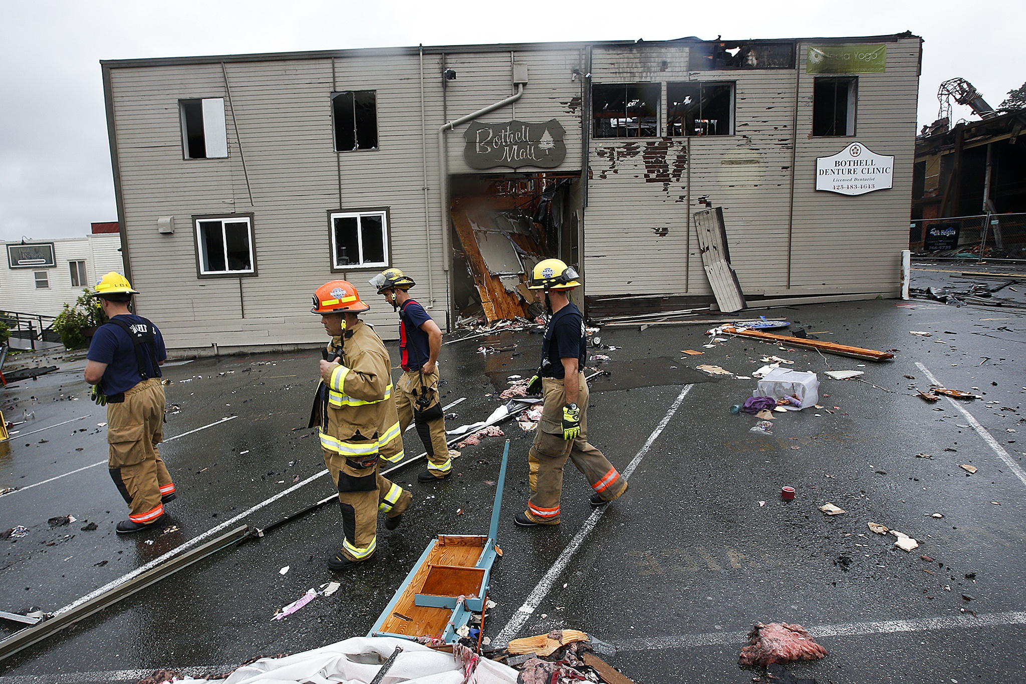 Firefighers pass by the entrance to the Bothell Mall following a fire on Friday
