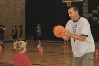 Coach Rich Klee shows Nate Moran how to handle the ball at last week’s Cubs Basketball Camp at Kenmore Junior High. ANDY NYSTROM