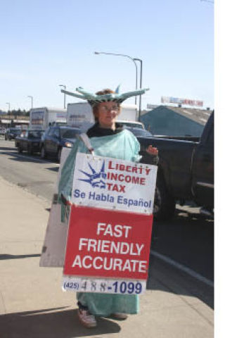 Cecily Longwill walks along the sidewalk at the corner of 68th Avenue Northeast and State Route 522 in Kenmore last week to promote Liberty Income Tax’s services in its nearby office. It’s her second year working for Liberty. “Cool