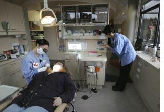 Dr. Lindsay Barry talks to Jacquelyn Deal as dental hygienist Helen Clancy looks on at Crisafulli Dental in Bothell Feb. 13. Crisafulli Dental and Chapman Dental of Bothell offered free treatment as a Valentine’s Day present for the needy throughout the day. See page 12 for more photos. FUMIKO YARITA