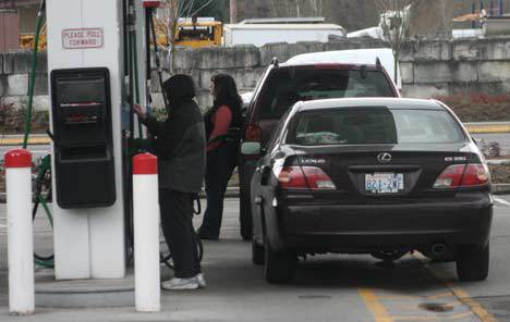 A pair of customers pump and pay for gas at a station in Kenmore. Prices are higher