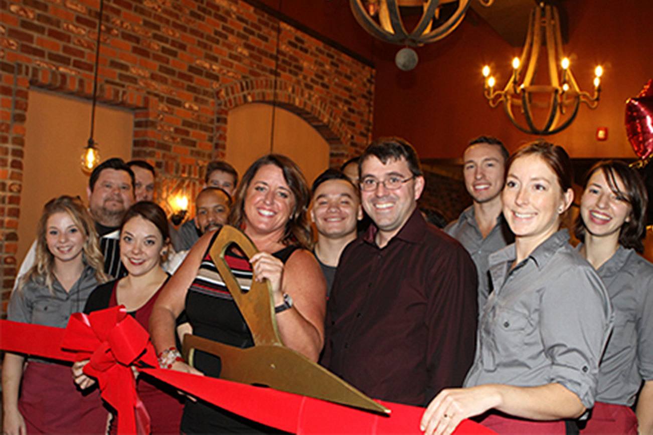 Owner Dusty DuBois (center, with the scissors) celebrates the grand opening of Revolve True Food and Wine Bar alongside the restaurant’s staff. Contributed photo