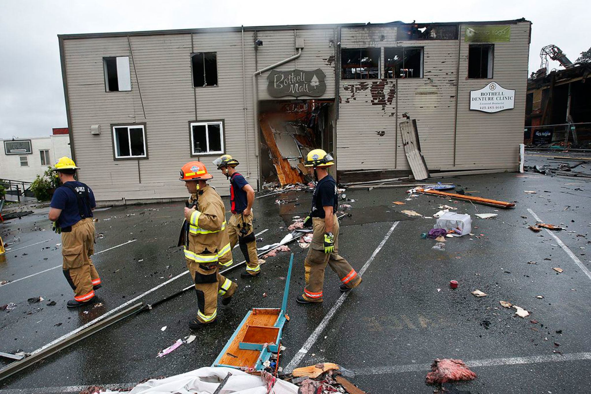 Firefighers pass by the entrance to the Bothell Mall following a fire on July 22. IAN TERRY/The Herald