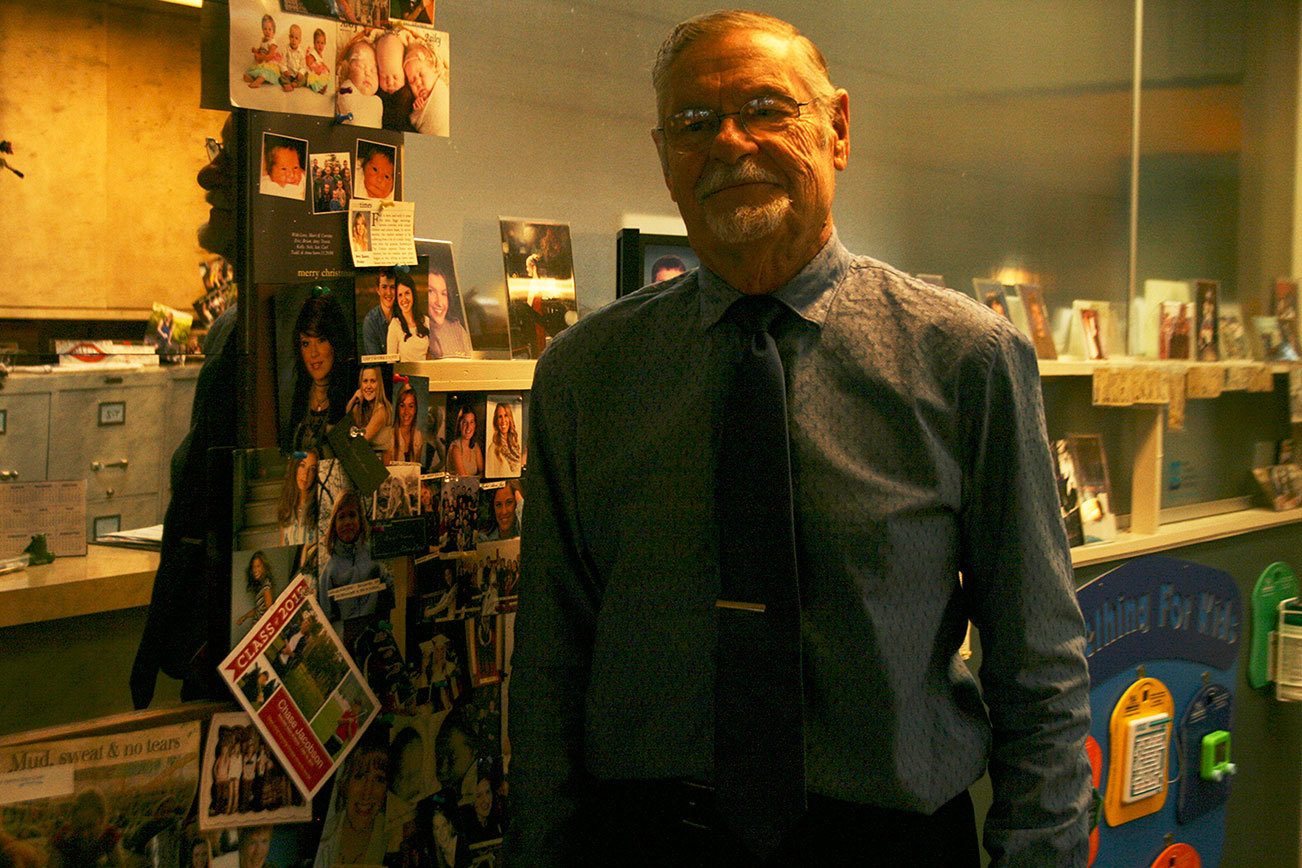 Dr. Robert J. Bendzak poses alongside a wall filled with pictures of his patients and their families. CATHERINE KRUMMEY / Kenmore Reporter