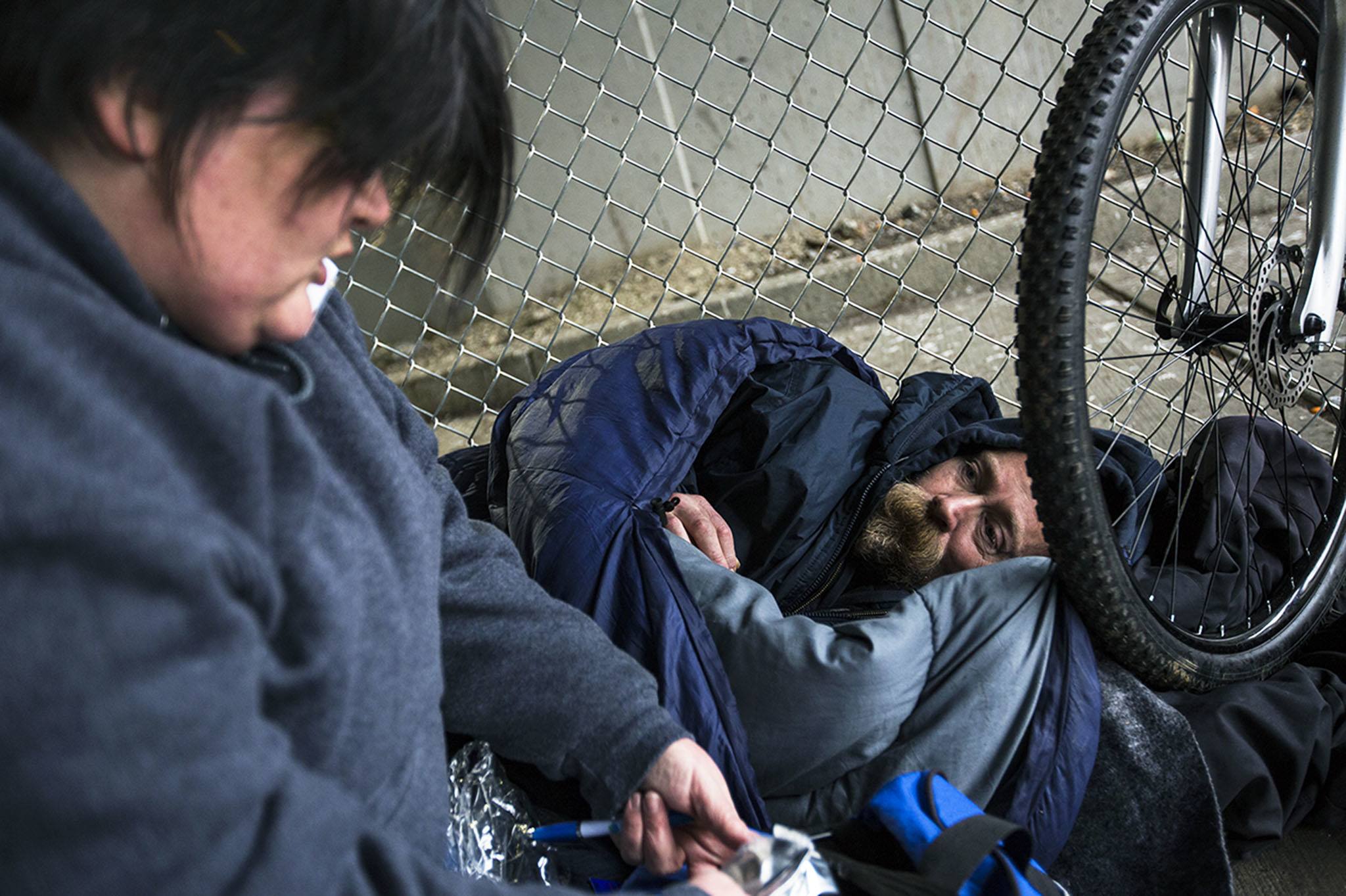 Gretchen Holtz, a volunteer from Compass Health, gathers information from Steve near the Everett Gospel Mission during the annual Point in Time Homeless Count on Tuesday, Jan. 24, 2017 in Everett. Volunteers conducted interviews and passed out resources in areas throughout Snohomish County. (Daniella Beccaria / The Herald)