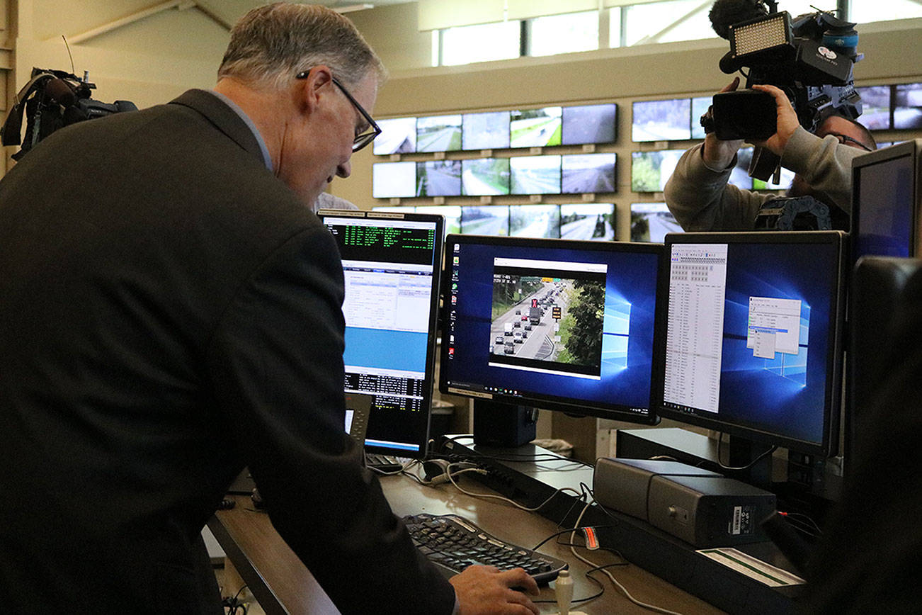 Gov. Jay Inslee clicks a button to open the Interstate 405 northbound peak-use shoulder lane to traffic for the first time. CATHERINE KRUMMEY / Bothell Reporter