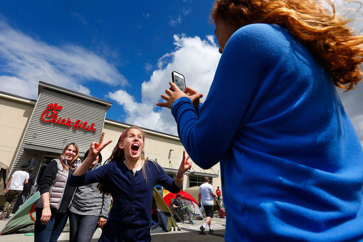 A girl jumps in front of the camera as another girl takes a picture at the opening of the Lynnwood Chick-Fil-A in 2015. The popular fast-food restaurant is opening in Bothell and continues to see explosive growth despite past controversies. (Everett Daily Herald file photo)