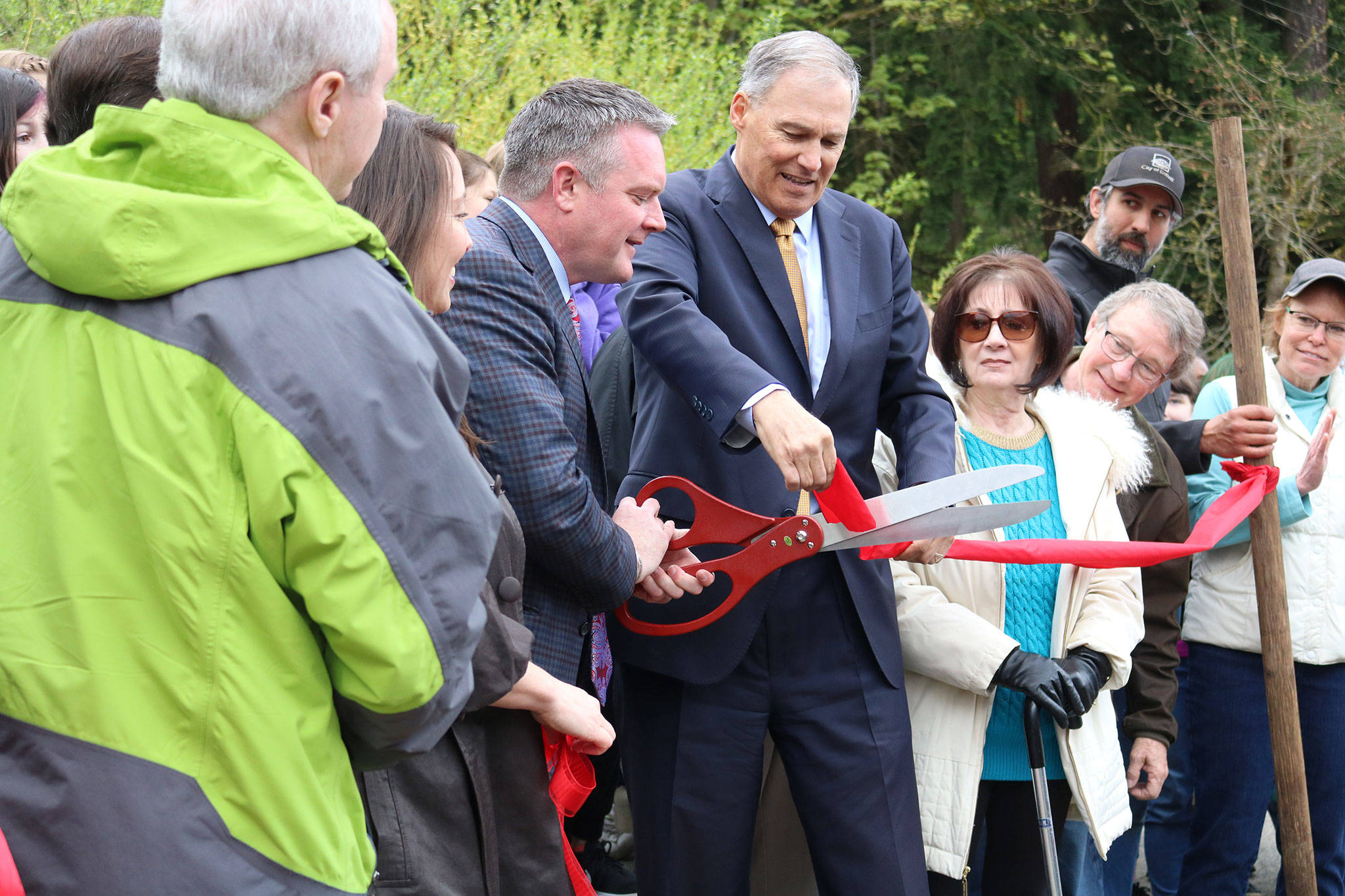 Bothell Mayor Andy Rheaume and Gov. Jay Inslee cut off a piece of the North Creek Forest ribbon for the governor to keep as a souvenir. CATHERINE KRUMMEY / Bothell Reporter