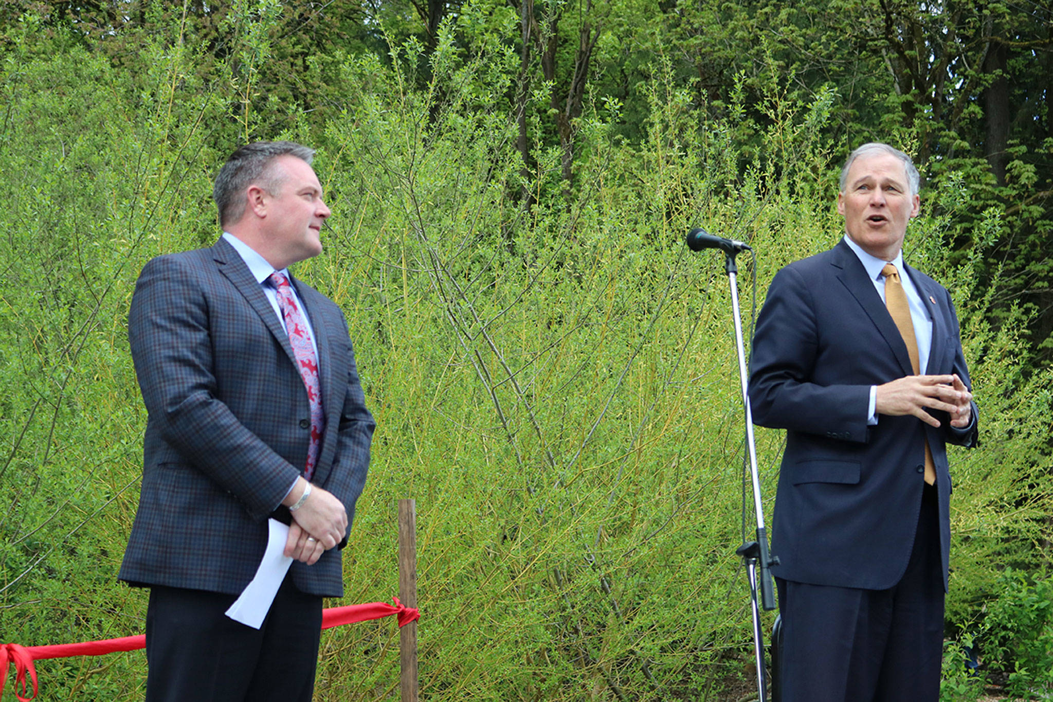 Gov. Jay Inslee (right) was the guest of honor at the North Creek Forest ribbon-cutting ceremony. He praises those who had a part in the land acquisition process as Bothell Mayor Andy Rheaume listens. CATHERINE KRUMMEY / Bothell Reporter