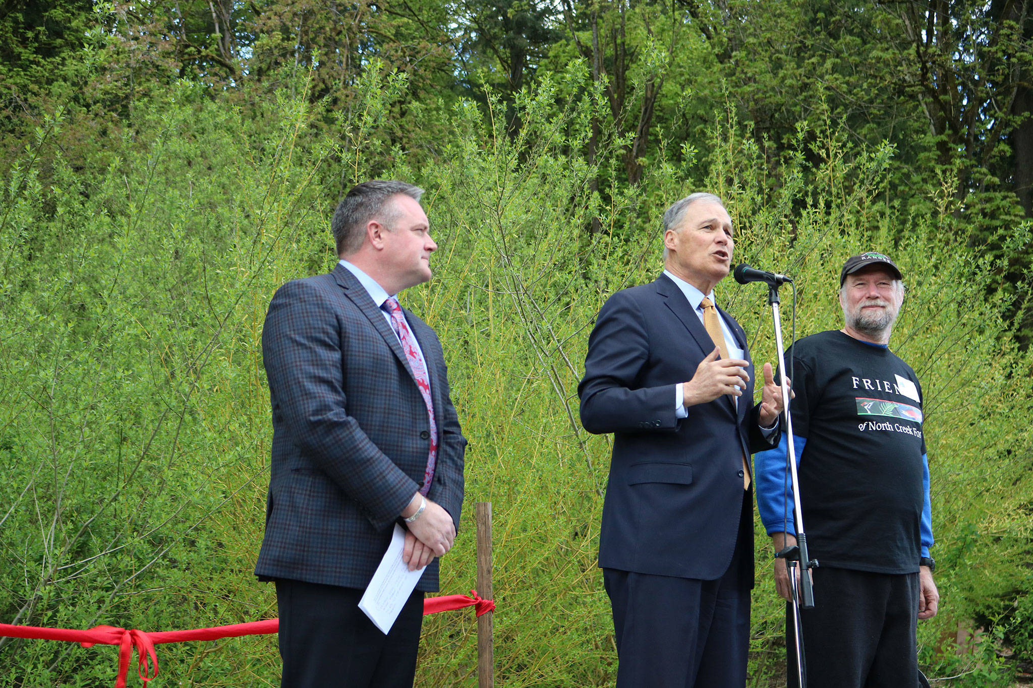 Gov. Jay Inslee (center) names Friends of North Creek Forest founding member David Bain (right) the “Washingtonian of the Day” for April 28. Bothell Mayor Andy Rheaume (left) listens to the governor’s remarks. CATHERINE KRUMMEY / Bothell Reporter